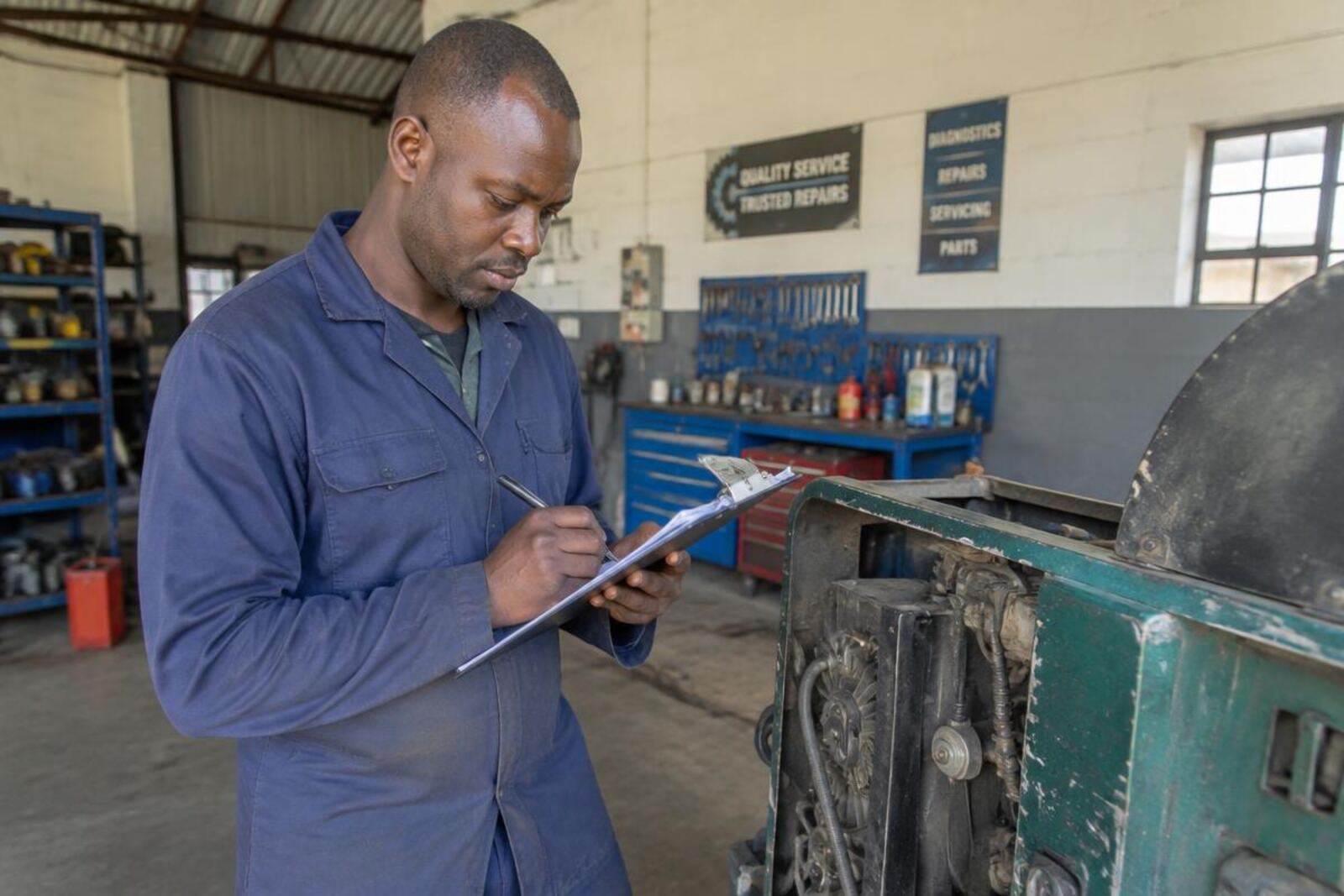 Workshop owner filling in a claim form next to a damaged machine